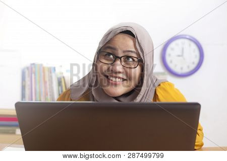 Muslim Businesswoman Working On Laptop At The Office, Thinking Gesture