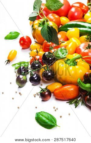 Assorted tomatoes and vegetables isolated on white background. Photo for your design
