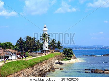 Famous lighthouse and palm trees in Galle Fort. Indian Ocean, sunny day, Sri Lanka