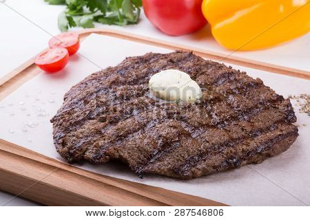 Prepared Steak Served With Butter On Wooden Board