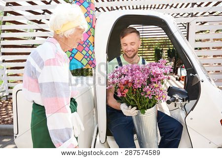 Portrait Of Smiling Handsome Man Delivering Flowers Sitting In Car On Plantation Lit By Sunlight, Co