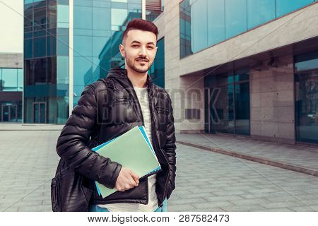 Arabian Student Holding Copybooks By Modern University Outside. Young Man With Backpack Looking At C