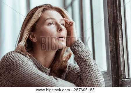 Beautiful Woman Wearing Sweater Standing Near The Window Sill