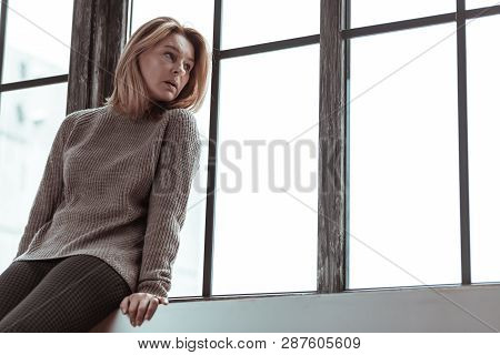 Blonde-haired Woman Sitting On The Window Sill At Home