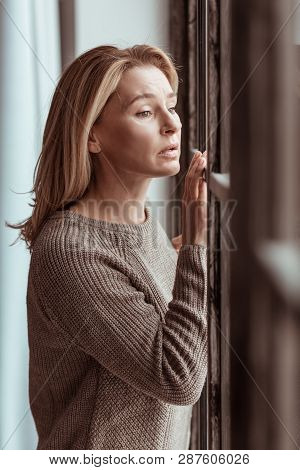Mature Woman Looking Into Window And Feeling Stressed