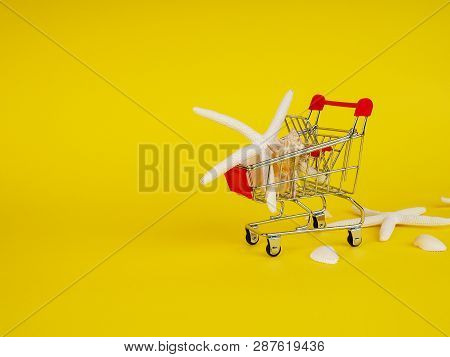 Shopping Cart , Troley With Seashells On Yellow Background.