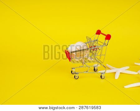 Shopping Cart , Troley With Seashells On Yellow Background.