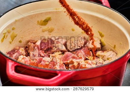 Preparing Perkelt Sauce - Pouring Dried Pepper On Meat In Red Pot