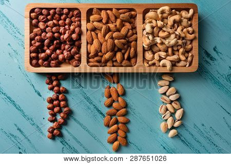 Compartmental Dish With Nuts On Blue Wooden Table. Cashew, Hazelnut, Almond.
