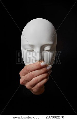 Woman fingers close mouth of gypsum mask face on a black background, copy space. Speak no evil. Concept three wise monkeys
