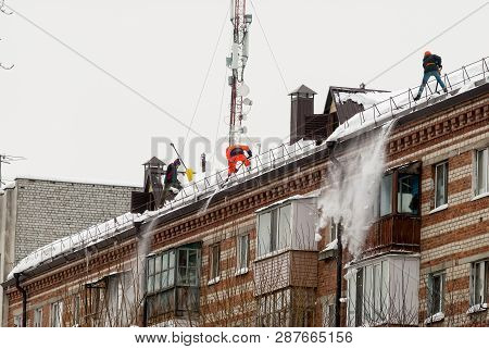 Tyumen, Russia - February 19, 2019: Men With Snow Shovels Clean Residential Building Roof In Winter 