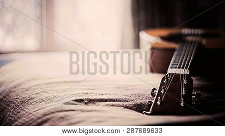 This Is Wooden Basic Classical Guitar On Bed. Beautiful Colouring Blurry Background Effect.
