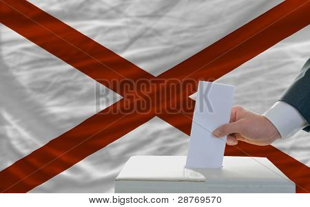Uomo di voto sulle elezioni davanti alla bandiera noi bandiera dello stato dell'Alabama