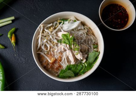 Asian rice noodles soup with vegetables and chicken in bowl. Top view flat lay.