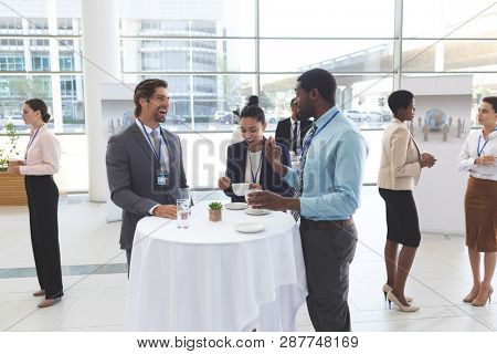 Front of view of diverse business people interacting with each other at table in office lobby