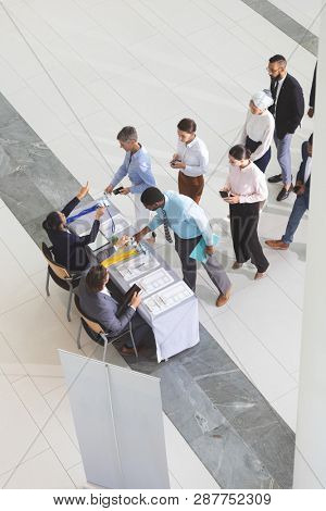 High angle view of diverse business people checking in at conference registration table in lobby 