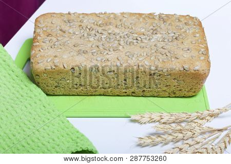 Baking Bread At Home. A Loaf Of Freshly Baked Wholegrain Bread With Sunflower Seeds Lies On A Cuttin