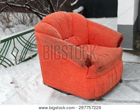 Old Armchair With Torn Armrest Seemingly Abandoned Outdoor And Placed On The Snow