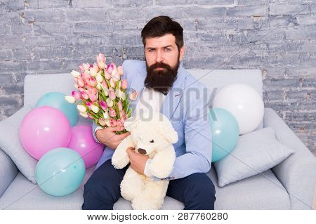 Romantic Man With Flowers And Teddy Bear Sit On Couch Waiting Girlfriend. Romantic Gift. Macho Getti
