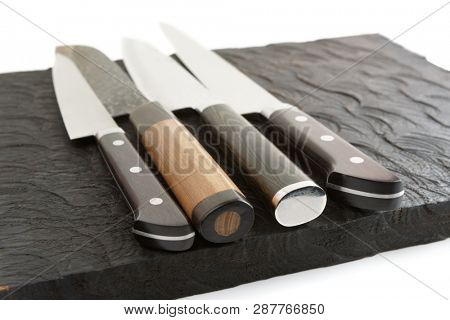 Set of new and used knives on wooden board, white background
