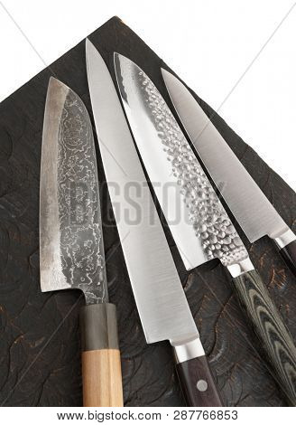 Four different knives on black wooden board, fragment