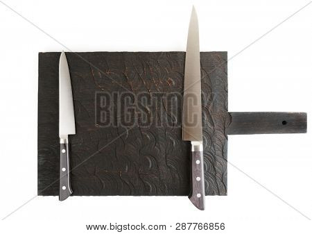 Two kitchen knives on black wooden board shot from above, isolated