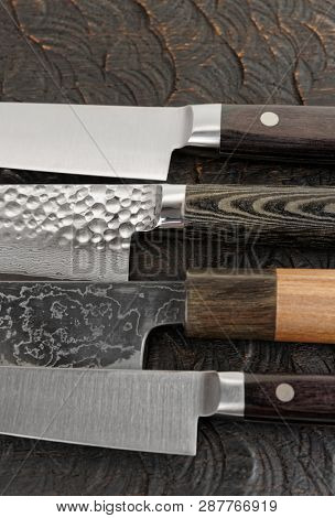 Knife handles and blades close-up on black wooden cutting board