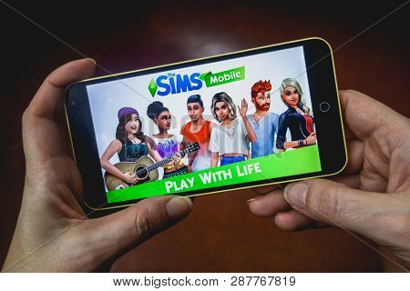 Berdyansk, Ukraine - March 4, 2019 - Close Up Of Hand Of Person Playing The Sims Mobile Game Apllica