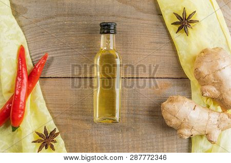 Small Ginger Oil Bottle In Center Of Keymap Of Condiments On Yellow Cloth On Old Wooden Table.