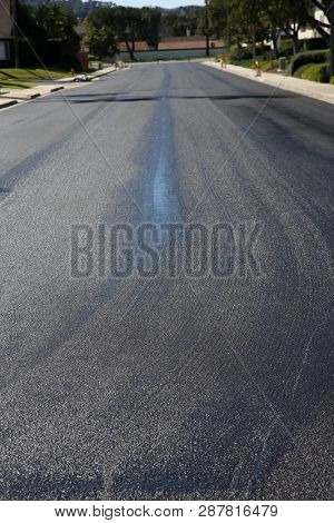 City street repair. Fresh slurry or blacktop on surface streets. road work filling pot holes and cracks. fresh oil. 
