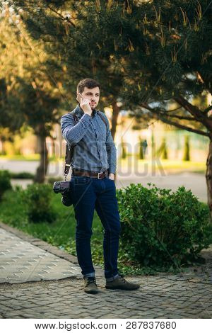 Professional Photographer With Leater Strap And Best Camera Use Phone To Call Model. Photographer Wa