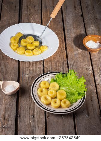 Potato Gnocchi On Two Plates, Leaves Of Fresh Leaf Lettuce On Light Plates On An Old Plank Table. Ne
