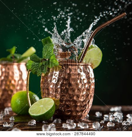 Famous splashing Moscow mule alcoholic cocktail in copper mugs, freeze motion effect.
