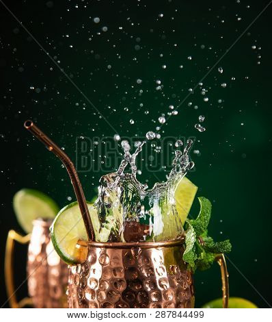Famous splashing Moscow mule alcoholic cocktail in copper mugs, freeze motion effect.