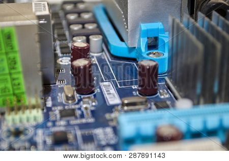Macro Photograph Of Blue Pc Motherboard. Detailing Its Conectors, Coolers And Components.