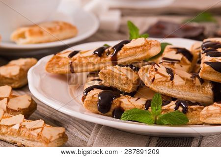 Puff Pastry Cookies With Chocolate Icing On White Dish.