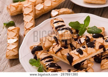 Puff Pastry Cookies With Chocolate Icing On White Dish.