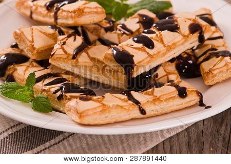 Puff Pastry Cookies With Chocolate Icing On White Dish.