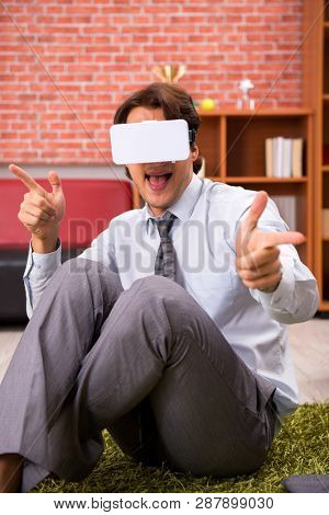 Young employee with virtual glasses during break in the office 