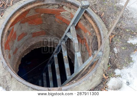 Open Sewer Hatch. Worker Carries Out Work On The Maintenance Of Communications.