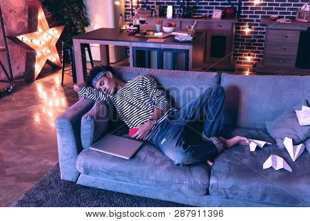 African American Guy Sitting Up At The Laptop Until Late And Dozing Off On The Sofa.
