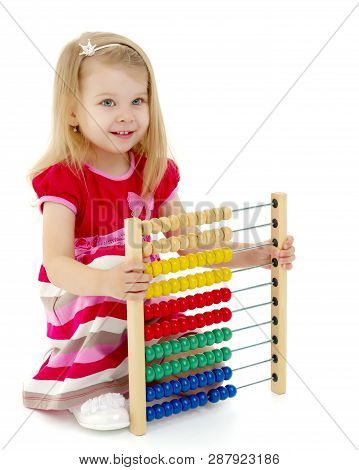 Cute Little Girl Is Playing With Wooden Abacus At Home. An Intelligent Child Learns To Count. She En