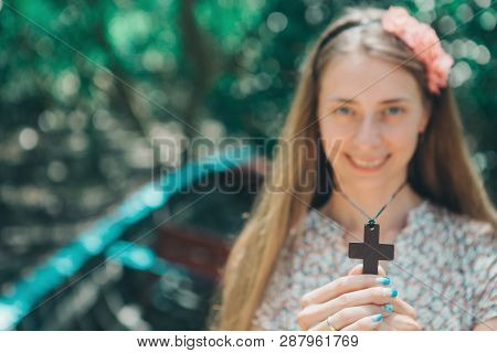 Cross In The Hands Of A Girl Close-up, Portrait Of A Woman Blurred