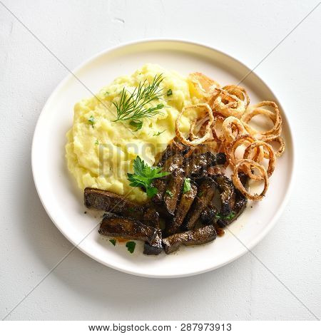 Fried Beef Liver With Mashed Potatoes And Onion Rings On White Plate Over Stone Background. Pieces L