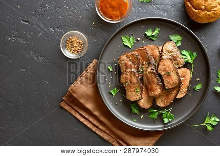 Beef Liver On Plate Over Black Stone Background. Roasted Liver(offal) From Beef Meat. Top View, Flat