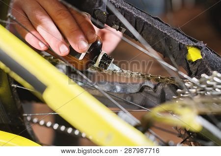 Close-up Of A Mans Hand, Led By Masters, Lubricate The Bicycle Chain Of A Mountain Bike With A Speci