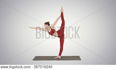 Slim Woman Standing In Yoga Pose Dandayamana Dhanurasana On Grad