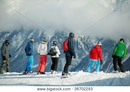 Gruppen av unga skidåkare står på kanten av snöiga hillslope