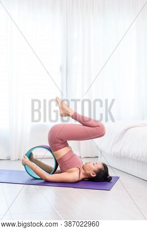Young Woman Do Wheel Yoga In A Bed Room