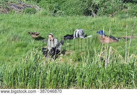 Woman Sitting On The Watersand Of The Pond Catching Fish